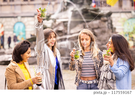 Friends enjoying drinks by a fountain, cherishing happy moments and socializing outdoors Friends enjoying drinks by a fountain, cherishing happy moments and socializing outdoors 117559167