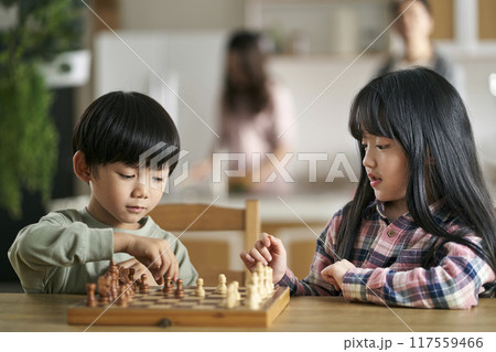 asian brother and sister playing chess at home 117559466