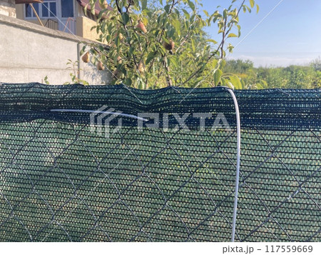 Strengthening a fence with a shading net with a rope Strengthening a fence with a shading net with a rope 117559669