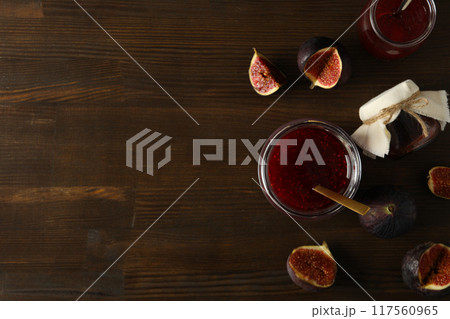 Glass jars with fig jam, spoon and cut figs on wooden background, space for text 117560965