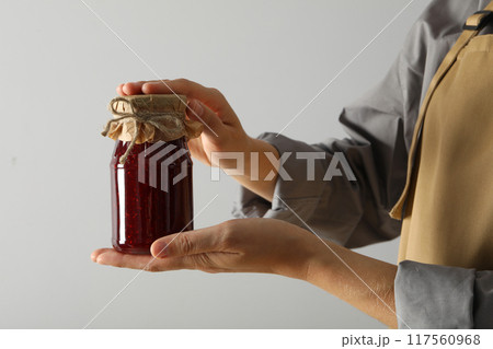 Glass jar with fig jam in hand on light background, close up Glass jar with fig jam in hand on light background, close up 117560968