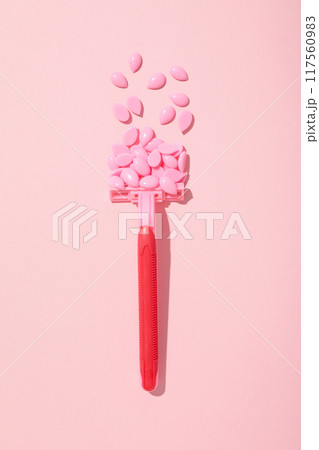 Wax granules for depilation with a razor on a pink background Wax granules for depilation with a razor on a pink background 117560983