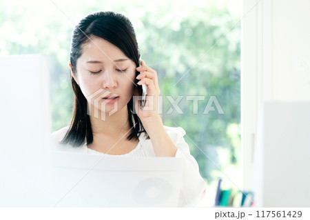 資料を手にスマホで通話する女性 資料を手にスマホで通話する女性 117561429