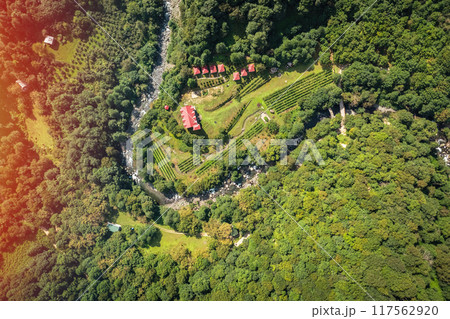 An Aerial View of a Lush Green Landscape Featuring a Meandering River and Villa Charming Buildings in Its Midst 117562920
