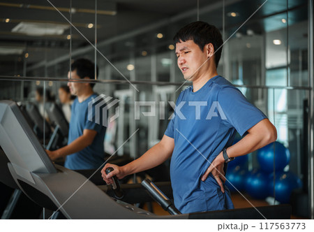 man with low back pain on treadmill at fitness gym exercise man with low back pain on treadmill at fitness gym exercise 117563773