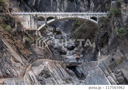 An old bridge opposite the landscape of Tiger Leaping Gorge in Yunnan province of China. An old bridge opposite the landscape of Tiger Leaping Gorge in Yunnan province of China. 117563962