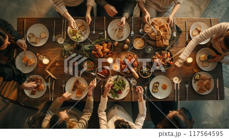 Friends sharing a meal around a wooden table. This is a casual dining setting with a warm and cozy atmosphere. Perfect for illustrating communal gatherings and intimate social events. AI 117564595