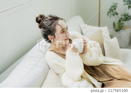 部屋でホットコーヒーを飲む女性 117565100