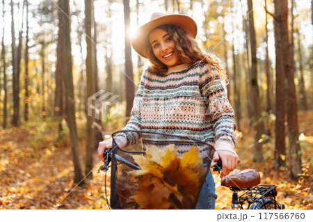 Happy active young woman on bike in autumn park at sunset. Concept of people, recreation, active lifestyle. Happy active young woman on bike in autumn park at sunset. Concept of people, recreation, active lifestyle. 117566760