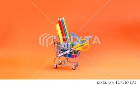 Shopping trolley with stationery items and school supplies on orange background. back to school and education background concept. Shopping cart, supermarket trolley with school supplies. Preparing for Shopping trolley with stationery items and school supplies on orange background. back to school and education background concept. Shopping cart, supermarket trolley with school supplies. Preparing for 117567173