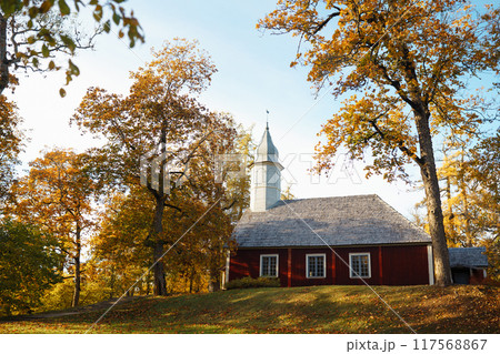 Neat wooden church in the autumn forest. Autumn church landscape. Church in the open air. Neat wooden church in the autumn forest. Autumn church landscape. Church in the open air. 117568867