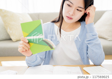 銀行通帳を見て悩む女性 銀行通帳を見て悩む女性 117569025