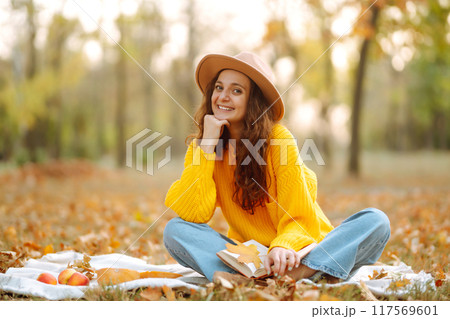 Fall picnic with pumpkin. Stylish woman enjoying autumn weather in the park. Autumn harvest. Fall picnic with pumpkin. Stylish woman enjoying autumn weather in the park. Autumn harvest. 117569601