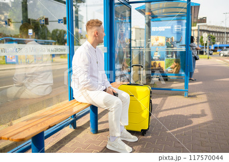 Handsome Tourist Caucasian business man traveler with bag and suitcase sit at public transport bus station waiting with mobile smart phone Handsome Tourist Caucasian business man traveler with bag and suitcase sit at public transport bus station waiting with mobile smart phone 117570044
