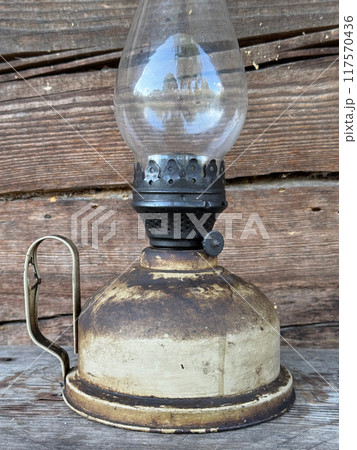 A vintage kerosene lamp against the backdrop of an old log shed. Close up 117570436