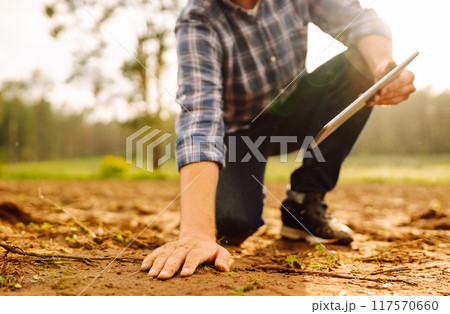 The farm owner's hand touches soil, checks quality of the soil before sowing. Ecology, technology. 117570660