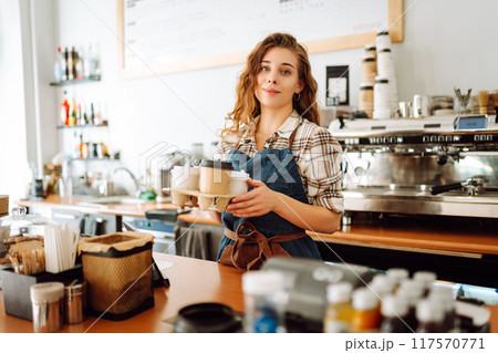 Portrait of beautiful young barista woman serving coffee with a big smile. Small business owner. Portrait of beautiful young barista woman serving coffee with a big smile. Small business owner. 117570771