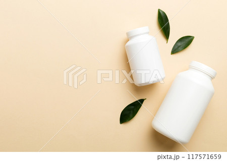 supplement pills with medicine bottle health care and medical top view. Vitamin tablets. Top view mockup bottle for pills and vitamins with green leaves, natural organic bio supplement, copy space 117571659