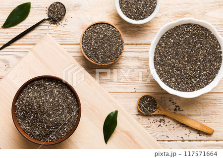 Chia seeds in bowl and spoon on colored background. Healthy Salvia hispanica in small bowl. Healthy superfood Chia seeds in bowl and spoon on colored background. Healthy Salvia hispanica in small bowl. Healthy superfood 117571664