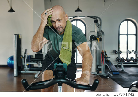 Man Training On Exercise Bike In Gym Man Training On Exercise Bike In Gym 117571742