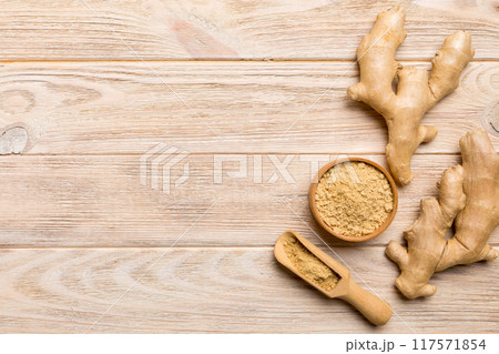 Finely dry Ginger powder in bowl with green leaves isolated on colored background. top view flat lay Finely dry Ginger powder in bowl with green leaves isolated on colored background. top view flat lay 117571854