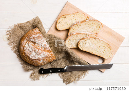 Freshly baked bread cut with knife on a wooden board. top view Sliced bread and knife 117571980