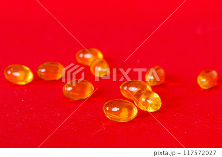 Heap of yellov pills on colored background. Tablets scattered on a table. Pile of red soft gelatin capsule. Vitamins and dietary supplements concept Heap of yellov pills on colored background. Tablets scattered on a table. Pile of red soft gelatin capsule. Vitamins and dietary supplements concept 117572027
