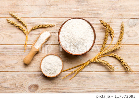 Flat lay of Wheat flour in wooden bowl with wheat spikelets on colored background. world wheat crisis 117572093