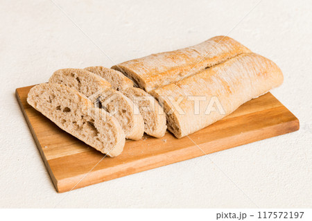 Assortment of freshly sliced baked bread with napkin on rustic table top view. Healthy unleavened bread. French bread slice 117572197