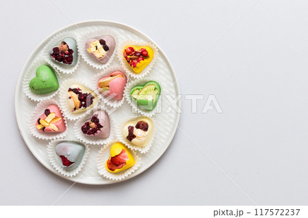 Plate with different chocolate on colored background. Assortment of fine chocolates top view vith copy space Health and obesity concept 117572237