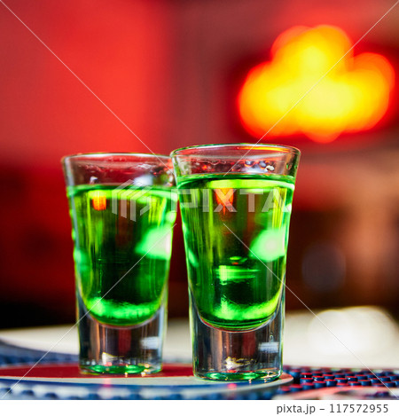 Green Alcoholic drink in shots on the bar counter 117572955