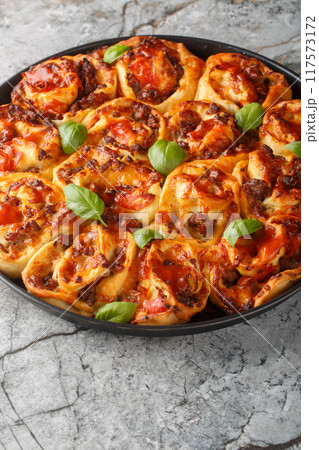 Italian pizza roll with tomatoes, cheese, sausages and basil close-up in baking dish. Vertical 117573172