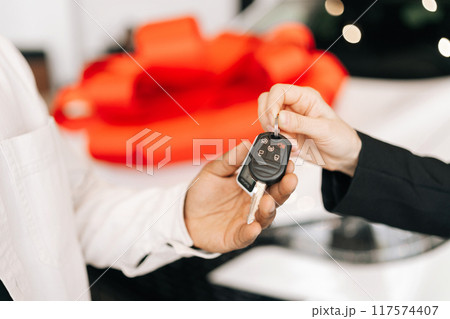 Close-up cropped shot of unrecognizable black male buyer getting car key and greetings from auto dealer while buying new auto in dealership. African car owner during handing over keys at auto showroom 117574407