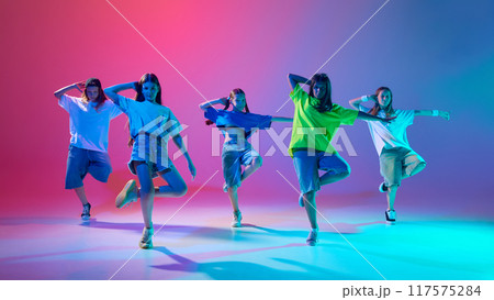 Group of children grooves to the beat, girls dynamically dancing hip hop against gradient pink purple background in neon light Group of children grooves to the beat, girls dynamically dancing hip hop against gradient pink purple background in neon light 117575284