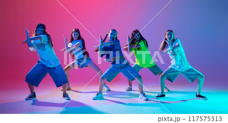 Group of children energetically showcase their hip hop moves, girls making dynamic performance against gradient pink purple background in neon light 117575313