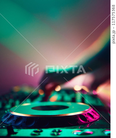 In haze of neon light, DJ commands deck, his silhouette blending with vibrant colors as he mixes tracks that energize crowd. In haze of neon light, DJ commands deck, his silhouette blending with vibrant colors as he mixes tracks that energize crowd. 117575368