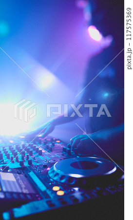 DJ lost in rhythm, surrounded by vibrant lights that pulse with beat, his hands expertly guiding music that fills room. DJ lost in rhythm, surrounded by vibrant lights that pulse with beat, his hands expertly guiding music that fills room. 117575369