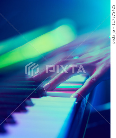 Introduction to melody. Cropped photo of elegant female hand on black and white keys of piano in vibrant spotlights. 117575425