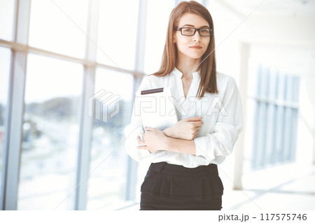 Beautiful female specialist with laptop computer standing in sunny office and smiling charmingly. Business people concept 117575746