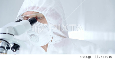 Professional scientist in protective gear is using microscope in a laboratory setting, close-up of researcher. Science and medicine concepts Professional scientist in protective gear is using microscope in a laboratory setting, close-up of researcher. Science and medicine concepts 117575940