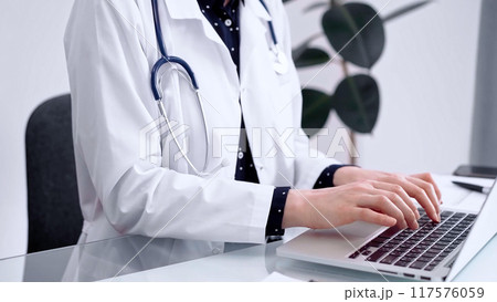 Doctor woman is using laptop computer at glass table in clinic. Medicine and pharmacy concept Doctor woman is using laptop computer at glass table in clinic. Medicine and pharmacy concept 117576059