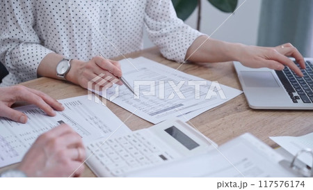 Professional female bookkeeper with a colleague are working on business finances. using calculator and laptop. Finance audit and taxes 117576174