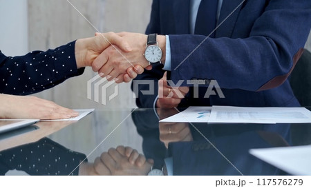Professional handshake between two professionals and applauds at a corporate meeting with reflection on table over a business meeting. Business people concept 117576279