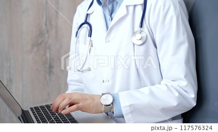 Doctor at work. Unrecognizable medical professional using laptop computer for healthcare research showcasing modern medical technology, close up 117576324