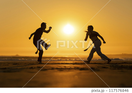Couple practicing capoeira martial art at sunset on the beach Couple practicing capoeira martial art at sunset on the beach 117576846