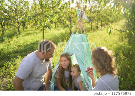 family with toddler playing in wigwam in garden 117576972