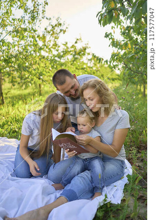 family reading the holy bible on a picnic in the garden 117577047