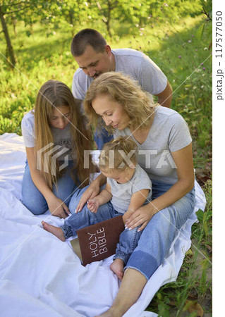 family reading the holy bible on a picnic in the garden 117577050