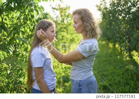 mother and teenage girls with long blond hair spend time together in the sunlit park mother and teenage girls with long blond hair spend time together in the sunlit park 117577191