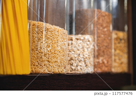 food, healthy eating and diet concept. jars with oatmeal, buckwheat, pasta and rice on thematic shelf in the kitchen, close-up food, healthy eating and diet concept. jars with oatmeal, buckwheat, pasta and rice on thematic shelf in the kitchen, close-up 117577476
